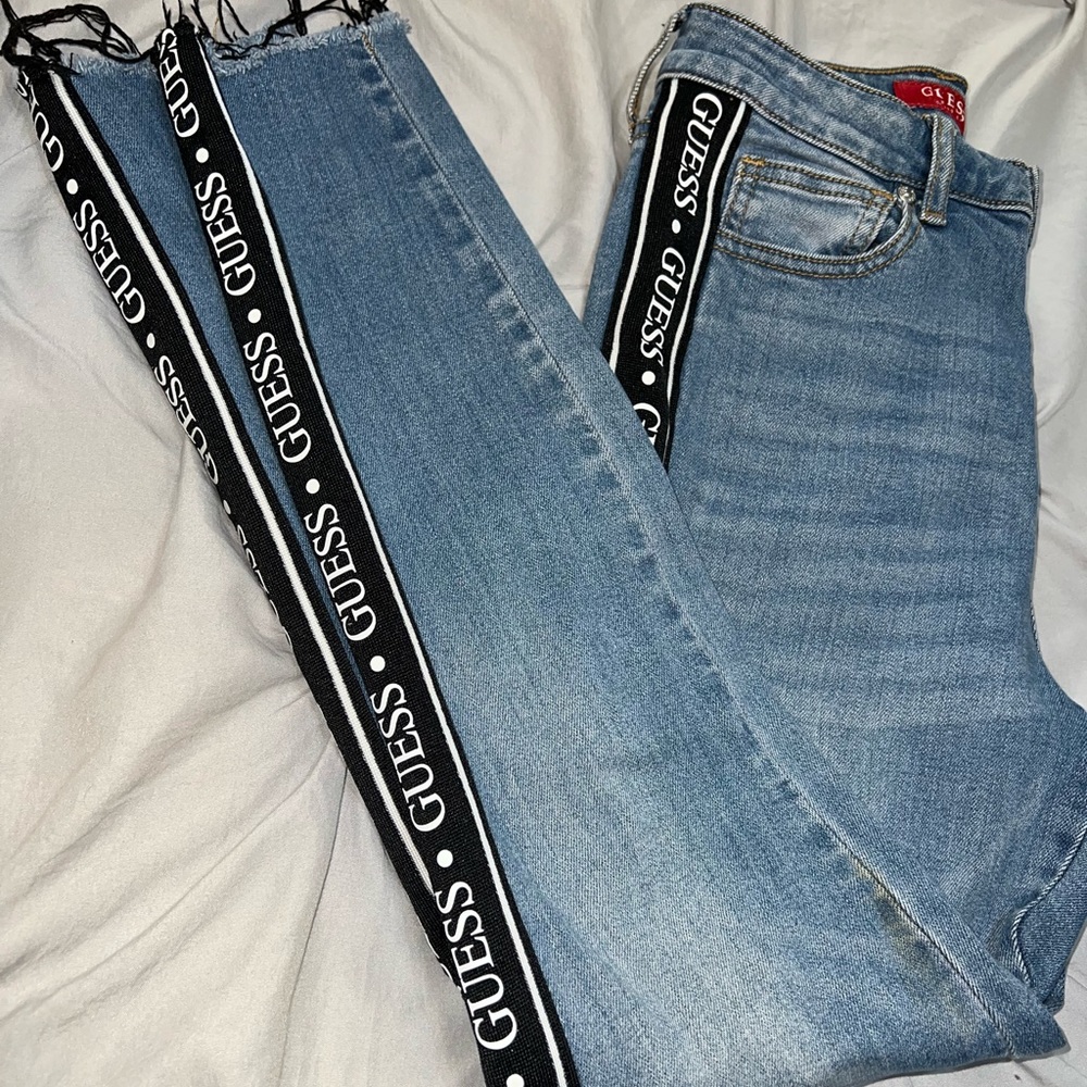 Guess logo on sides with black and white strip, light wash, trimmed in ankle,